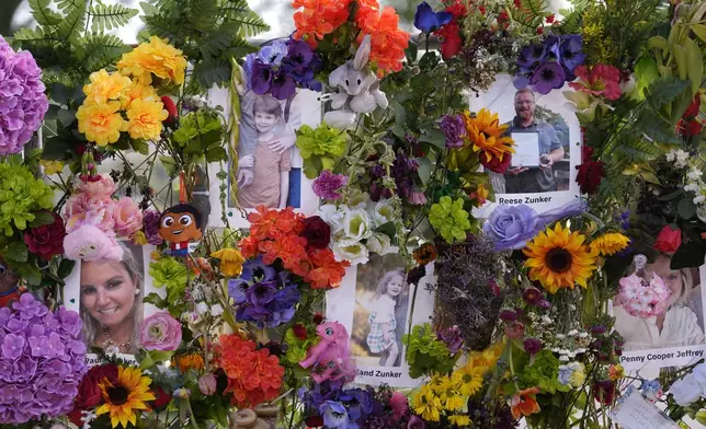 Photos of the Zunker family hang on a memorial wall of flowers for flood victims on Friday, July 11, 2025, in Kerrville, Texas. (AP Photo/Gerald Herbert)