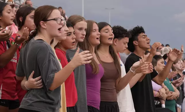 Attendees sing during a vigil for flooding victims at Tivy Antler Stadium on Wednesday, July 9, 2025, in Kerrville, Texas. (AP Photo/Gerald Herbert)