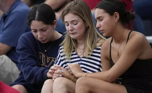Attendees react during a vigil for flooding victims at Tivy Antler Stadium on Wednesday, July 9, 2025, in Kerrville, Texas. (AP Photo/Ashley Landis)