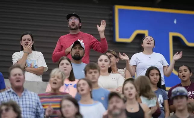 Attendees hold their hands in prayer as they sing during a vigil for flooding victims at Tivy Antler Stadium on Wednesday, July 9, 2025, in Kerrville, Texas. (AP Photo/Ashley Landis)
