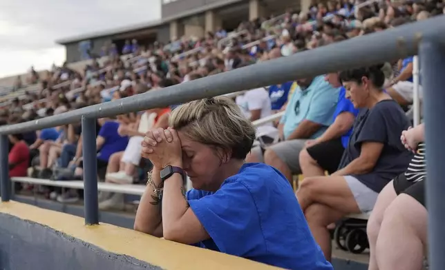 A woman prays during a vigil for flooding victims at Tivy Antler Stadium on Wednesday, July 9, 2025, in Kerrville, Texas. (AP Photo/Ashley Landis)