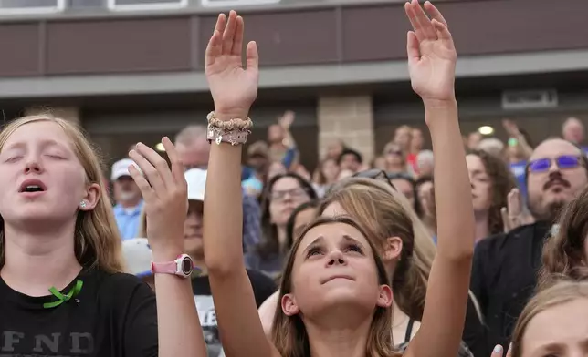 Attendees hold their hands in prayer as they sing during a vigil for flooding victims at Tivy Antler Stadium on Wednesday, July 9, 2025, in Kerrville, Texas.