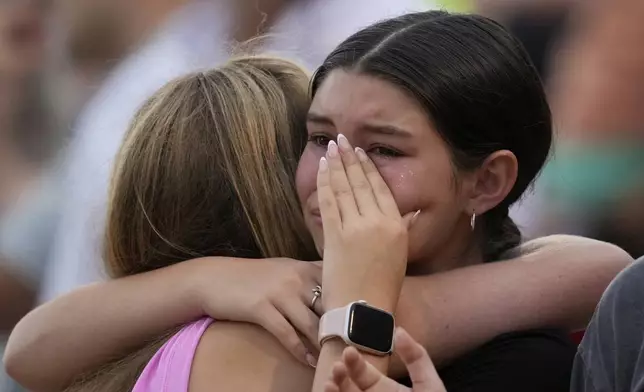 Girls hug during a vigil for flooding victims at Tivy Antler Stadium on Wednesday, July 9, 2025, in Kerrville, Texas. (AP Photo/Ashley Landis)