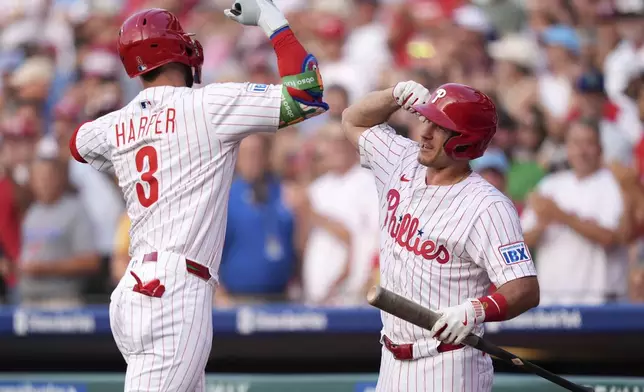 Philadelphia Phillies' Bryce Harper, left, and J.T. Realmuto celebrate after Harper's home run during the first inning of a baseball game against the Boston Red Sox Wednesday, July 23, 2025, in Philadelphia. (AP Photo/Matt Slocum)