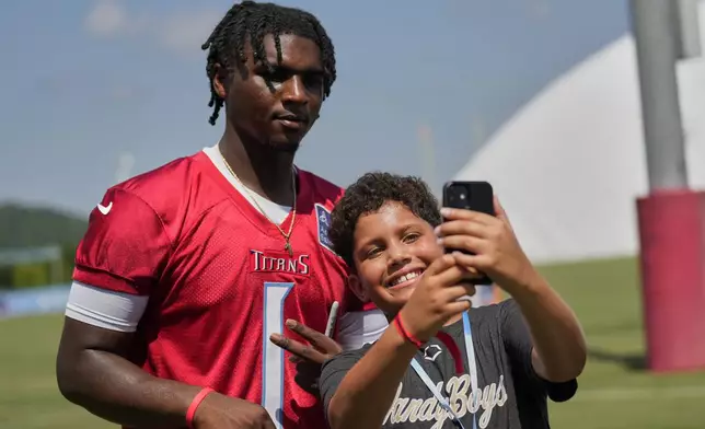 Tennessee Titans quarterback Cam Ward (1) poses with Nylan Williams, 10, right, after practice at the team's NFL football training camp Wednesday, July 23, 2025, in Nashville, Tenn. (AP Photo/George Walker IV)