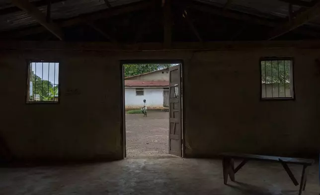 A young girl walks by an empty community meeting room in Bong County, Liberia, Saturday, June 14, 2025. (AP Photo/Annie Risemberg)