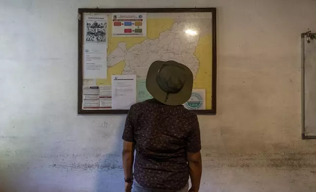 Morris Wamah, the director for the Liberian Initiative for Development Services, who worked implementing USAID funding in Liberian land reform, looks at a map of Bong County in Gbarnga, Liberia, Saturday, June 14, 2025. (AP Photo/Annie Risemberg)