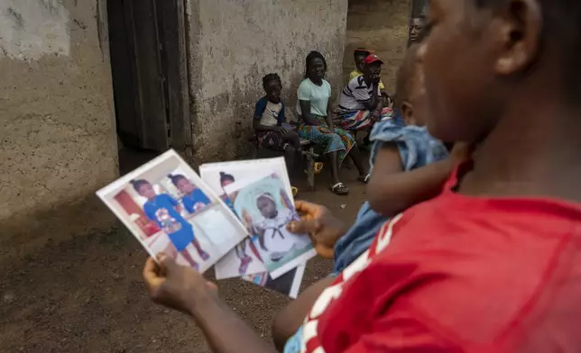 Roseline Phay, 32, looks at pictures of her first daughter, Promise, who she sent to Monrovia to stay with family in hopes of getting her a better education, Saturday, June 14, 2025. (AP Photo/Annie Risemberg)