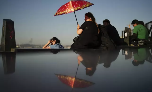 A woman shelters against the sun during a hot summer day in Istanbul, Tuesday, July 8, 2025. (AP Photo/Francisco Seco)