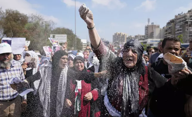 A woman throws flour, as she protests outside the Egyptian Embassy in Beirut, Lebanon, Wednesday, July 23, 2025, during a demonstration against the Israeli war and what they say starvation of civilians in the Gaza Strip. (AP Photo/Hussein Malla)
