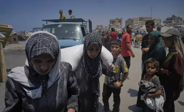 Iman Shabat, a mother of five carries a sack of flour unloaded from a humanitarian aid convoy that reached Gaza City from the northern Gaza Strip, Tuesday, July 22, 2025. (AP Photo/Jehad Alshrafi)
