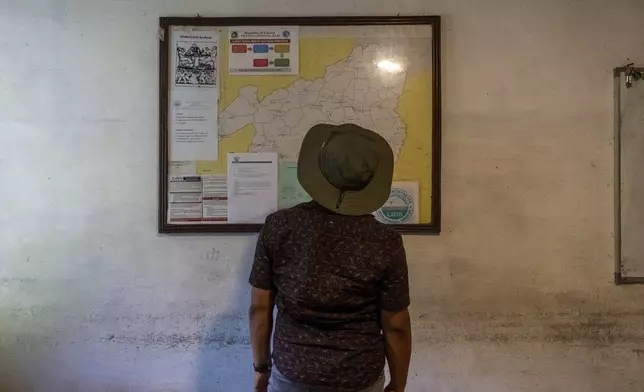 Morris Wamah, the director for the Liberian Initiative for Development Services, who worked implementing USAID funding in Liberian land reform, looks at a map of Bong County in Gbarnga, Liberia, Saturday, June 14, 2025. (AP Photo/Annie Risemberg)