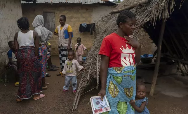 Roseline Phay, 32, stands with her daughter Pauline outside their home in Bong County, Liberia, Saturday, June 14, 2025. (AP Photo/Annie Risemberg)