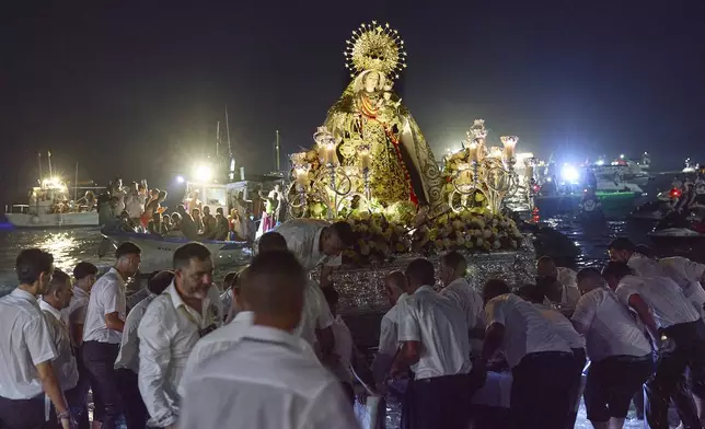 Catholic faithful return the statue of the Virgin of Carmen to the shore at the end of a religious procession in Estepona, Málaga, southern Spain, Wednesday, July 16, 2025. (AP Photo/Claudia Rosel)