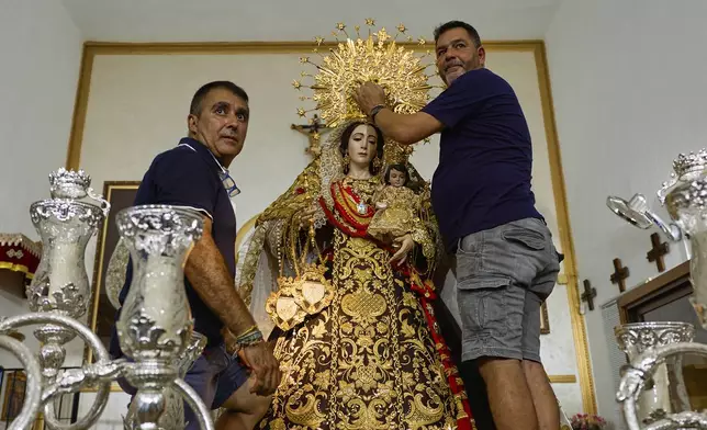Members of the Carmen brotherhood prepare the icon of the Virgin of Carmen a day before a religious parade through the streets and along the shore of Estepona, southern Spain, Tuesday, July 15, 2025. (AP Photo/Claudia Rosel)