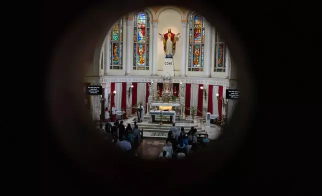 People offer prayers for crew members of the Air India flight that crashed in Ahmedabad last month during a prayer meeting at a church in Mumbai, India, Saturday, July 12, 2025. (AP Photo/ Rafiq Maqbool)