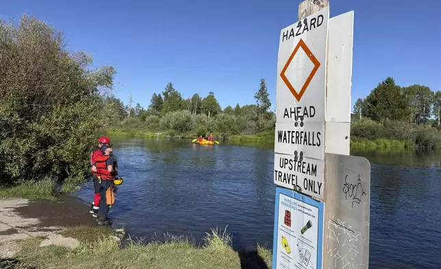 This photo provided by the Deschutes County Sheriff's Office shows search and rescue teams and a sign indicating a hazardous waterfall ahead along the Deschutes River about 10 miles from Bend, Ore., after a fatal waterfall accident Saturday, July 19, 2025. (Deschutes County Sheriff's Office via AP)