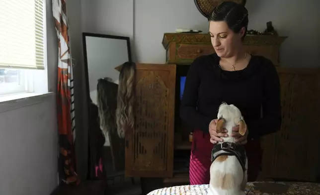 Havalah Hopkins, a single mother who lives in government-subsidized housing with her teenage son, pets her dog, Benny, in her bedroom Monday, July 14, 2025, in Woodinville, Wash. (AP Photo/Lindsey Wasson)
