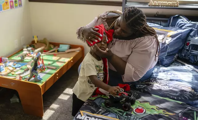 Aaliyah Barnes wipes her son, Aarmoni's, face with a blanket in their apartment at the Stoddard Johnston Scholar House, Friday, July 11, 2025, in Louisville, Ky. (AP Photo/Jon Cherry)