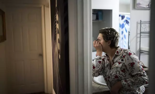 Havalah Hopkins, a single mother who lives in government-subsidized housing with her teenage son, does her makeup at her apartment Thursday, July 10, 2025, in Woodinville, Wash. (AP Photo/Lindsey Wasson)