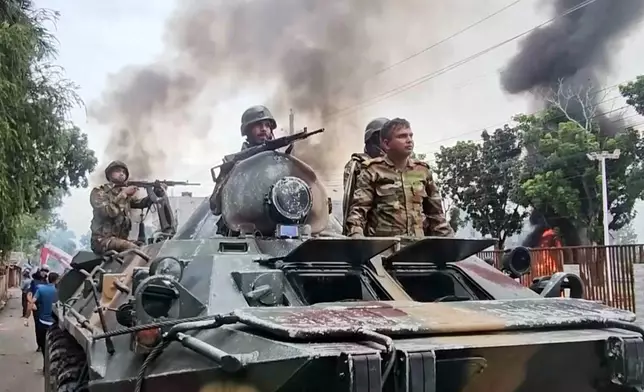 In this image made from a video, smoke rises behind an armored vehicle as supporters of the ousted Prime Minister Sheikh Hasina clash with security forces in Gopalganj, Bangladesh, Wednesday, July 16, 2025. (AP Photo)