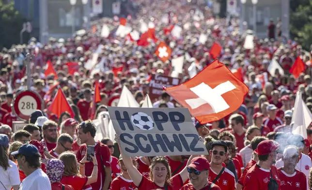 A fan holds a poster with the words in German "Go Switzerland" while walking with thousands to the stadium for he Women's Euro 2025 quarterfinal soccer match between Switzerland and Spain in Bern, Switzerland, Friday July 18, 2025. (Urs Flueeler/Keystone via AP)