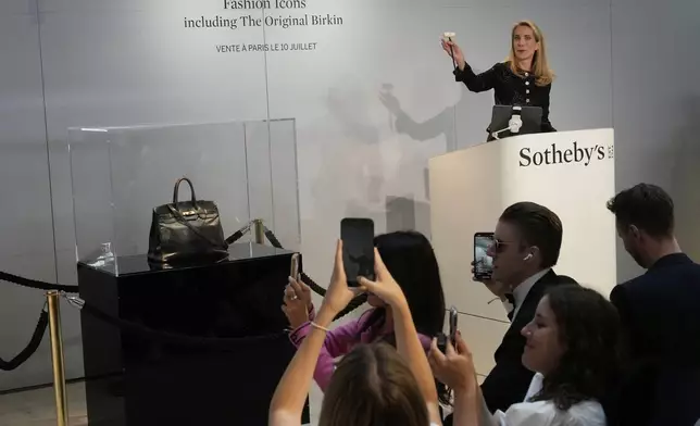 Auction officer Aurélie Vandevoorde gestures as the original Birkin bag created by Hermès for Jane Birkin was sold at auction for 7 million euros or $8.2 million, Thursday, July 10, 2025 in Paris. (AP Photo/Michel Euler)