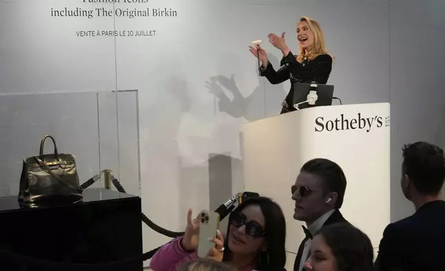 Auction officer Aurélie Vandevoorde gestures as the original Birkin bag created by Hermès for Jane Birkin was sold at auction for 7 million euros or $8.2 million, Thursday, July 10, 2025 in Paris. (AP Photo/Michel Euler)