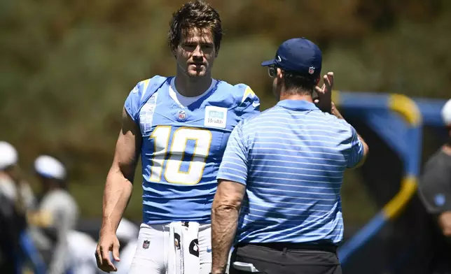 Los Angeles Chargers quarterback Justin Herbert (10) talks with head coach Jim Harbaugh during practice at the team's NFL football training camp, Wednesday, July 23, 2025, in San Diego. (AP Photo/Denis Poroy)