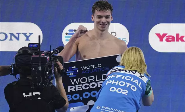 Leon Marchand of France celebrates after receiving an award for creating a new world record following the men's 200-meter individual medley semifinals at the World Aquatics Championships in Singapore, Wednesday, July 30, 2025. (AP Photo/Ng Han Guan)