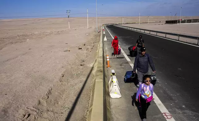 Fernando Colmenares, center, walk along the Chacalluta border as they leave Chile due to what they describe as discrimination against Venezuelans fueled by rising crime, in Arica, Chile Sunday, June 8, 2025. (AP Photo/Esteban Felix)