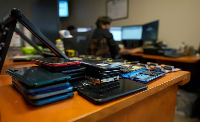 Seized mobile phones and electronic devices sit on a desk inside the office of the prosecutors investigating the Tren de Aragua gang, in Arica, Chile, Monday, June 9, 2025. (AP Photo/Esteban Felix)
