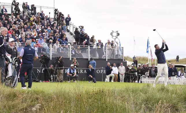 Eric Trump tees off as President Donald Trump, left, stands, during the opening ceremony for the Trump International Golf Links golf course, near Aberdeen, Scotland, Tuesday, July 29, 2025. (AP Photo/Jacquelyn Martin)