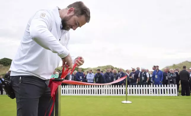 A staff member sets up the red ribbon ahead of an opening ceremony at the Trump International Golf Links golf course, near Aberdeen, Scotland, Tuesday, July 29, 2025. (AP Photo/Jacquelyn Martin)