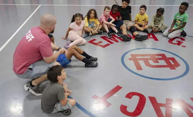 Thomas Boucher leads children in an activity during the East Providence Boys and Girls Club Summer Camp at Emma G. Whiteknact Elementary School on Thursday, July 10, 2025, in Providence R.I. (AP Photo/Sophie Park)