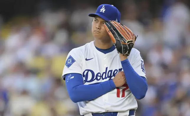 Los Angeles Dodgers pitcher Shohei Ohtani listens to the PitchCom during the first inning of a baseball game against the Minnesota Twins in Los Angeles, Monday, July 21, 2025. (AP Photo/Jayne Kamin-Oncea)