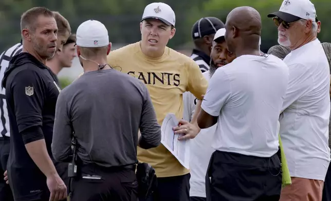 New Orleans Saints head coach Kellen Moore, center, talks with staff and executive vice president/general manager Mickey Loomis, right, during the team's NFL football training camp in Metairie, La., Wednesday, July 23, 2025. (AP Photo/Matthew Hinton)