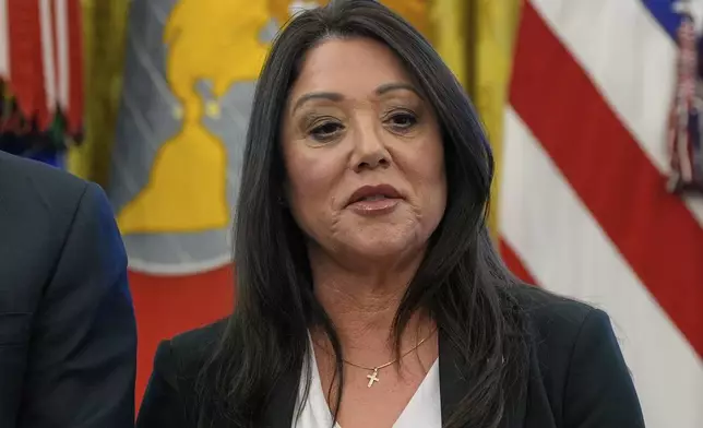 FILE - Labor Secretary Lori Chavez-DeRemer listens as President Donald Trump speaks with reporters while signing executive orders in the Oval Office of the White House, April 23, 2025, in Washington. (AP Photo/Alex Brandon, File)