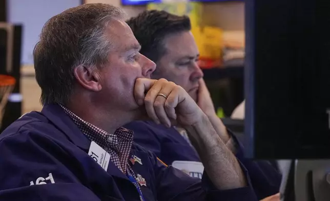 Trader Thomas McCauley, left, works on the floor of the New York Stock Exchange, Tuesday, July 8, 2025. (AP Photo/Richard Drew)