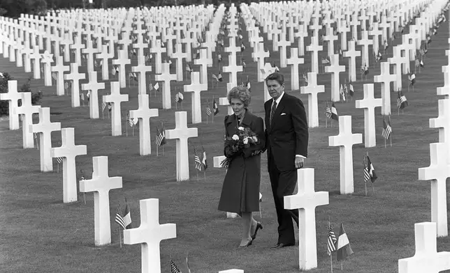FILE - U.S. President Ronald Reagan and first lady Nancy Reagan walk among the thousands of graves at the American Cemetery in Omaha Beach, Normandy, France on June 6, 1984 during ceremonies for the 40th anniversary of the D-Day allied invasion of occupied France. (AP Photo/Bob Daugherty, File)