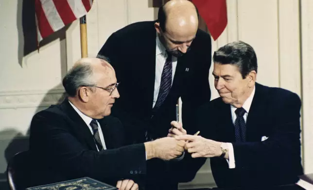 FILE - U.S. President Ronald Reagan, right, and Soviet leader Mikhail Gorbachev exchange pens during the Intermediate Range Nuclear Forces Treaty signing ceremony in the White House East Room in Washington, on Dec. 8, 1987. Gorbachev's translator Pavel Palazhchenko stands in the middle. (AP Photo/Bob Daugherty, File)