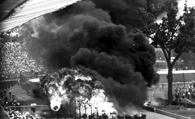FILE - A burning tire, left, flies toward spectators after a gasoline tank explosion resulting from a crash on the fourth turn on the second lap of the 48th running of the Indianapolis 500 auto race at Indianapolis Motor Speedway in Indianapolis, on May 30, 1964. (AP Photo/Bob Daugherty, File)
