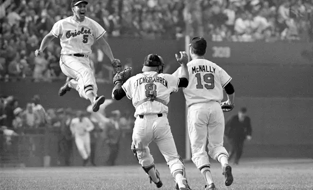 FILE - Baltimore Orioles third baseman Brooks Robinson (5) leaps across the infield to congratulate pitcher Dave McNally (19) and Orioles catcher Andy Etchebarren (8) after the final out in a World Series baseball game against the Los Angeles Dodgers in Baltimore, Md., on Oct. 9, 1966. (AP Photo/Bob Daugherty, File)