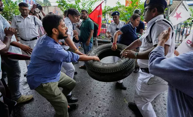 Policemen snatch a car tire that was used to make a road block from a supporter of Centre of India Trade Unions, CITU, during a nation-wide strike to protest what they call the anti-labor and anti-poor policies of the federal government, in Kolkata, India, Wednesday, July 9, 2025. (AP Photo/Bikas Das)