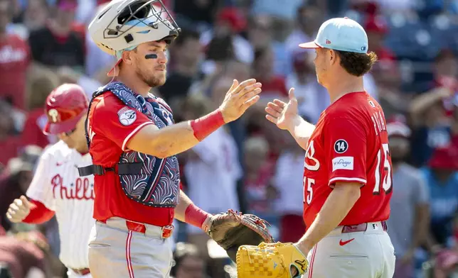 Cincinnati Reds catcher Tyler Stephenson, left, and closing pitcher Emilio Pagan (15) celebrate after their win over the Philadelphia Phillies in a baseball game, Friday, July 4, 2025, in Philadelphia. (AP Photo/Laurence Kesterson)