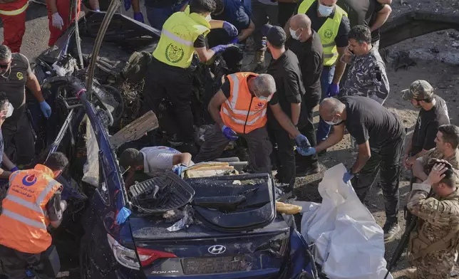 Civil Defense workers collect body remains from a destroyed car that was hit in an Israeli drone strike in Khaldeh town, south of Beirut, Lebanon, Thursday, July 3, 2025. (AP Photo/Hussein Malla)