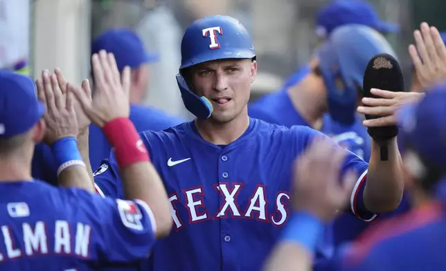 Texas Rangers' Corey Seager is congratulated by teammates in the dugout after scoring on a single by Adolis Garcia during the first inning of a baseball game against the Los Angeles Angels, Thursday, July 10, 2025 in Anaheim, Calif. (AP Photo/Mark J. Terrill)