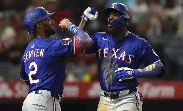 Texas Rangers' Adolis Garcia, right, is congratulated by Marcus Semien after hitting a two-run home run during the eighth inning of a baseball game against the Los Angeles Angels, Thursday, July 10, 2025 in Anaheim, Calif. (AP Photo/Mark J. Terrill)