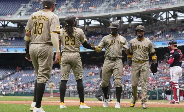 San Diego Padres designated hitter Xander Bogaerts, second from right, celebrates his grand slam against the Washington Nationals with Manny Machado (13), Fernando Tatis Jr. (23) and Luis Arraez, right, during the first inning of a baseball game at Nationals Park, Sunday, July 20, 2025, in Washington. (AP Photo/Jess Rapfogel)