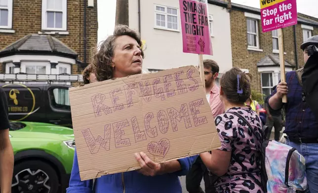A demonstrator holds a placard as she leaves a protest outside the Bell Hotel in Epping, near London, Sunday, July 27, 2025.(AP Photo/Alberto Pezzali)